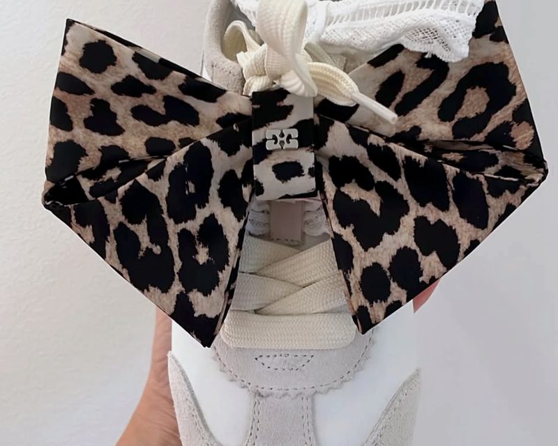 Witte sneaker met een grote luipaardstrik en kanten veters